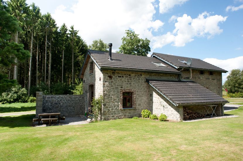 The stone house of the Gîte de la Forge and its lawn, at the edge of the woods